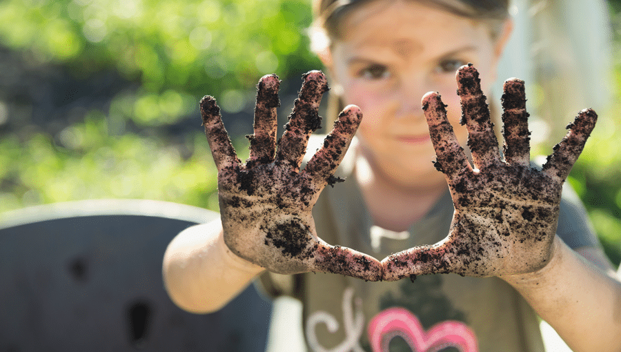 stock image of girl holding up both hands with dirt on them