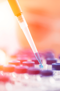 pipette inserting blue liquid into tray of vials